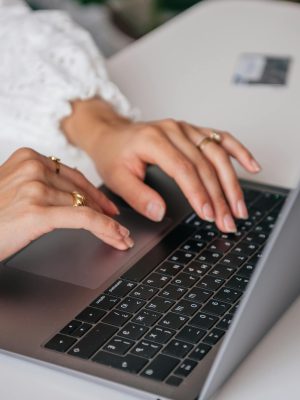 Mains d'une femme sur le clavier d'un ordinateur portable. Elle relit et corrige des fautes dans Word.